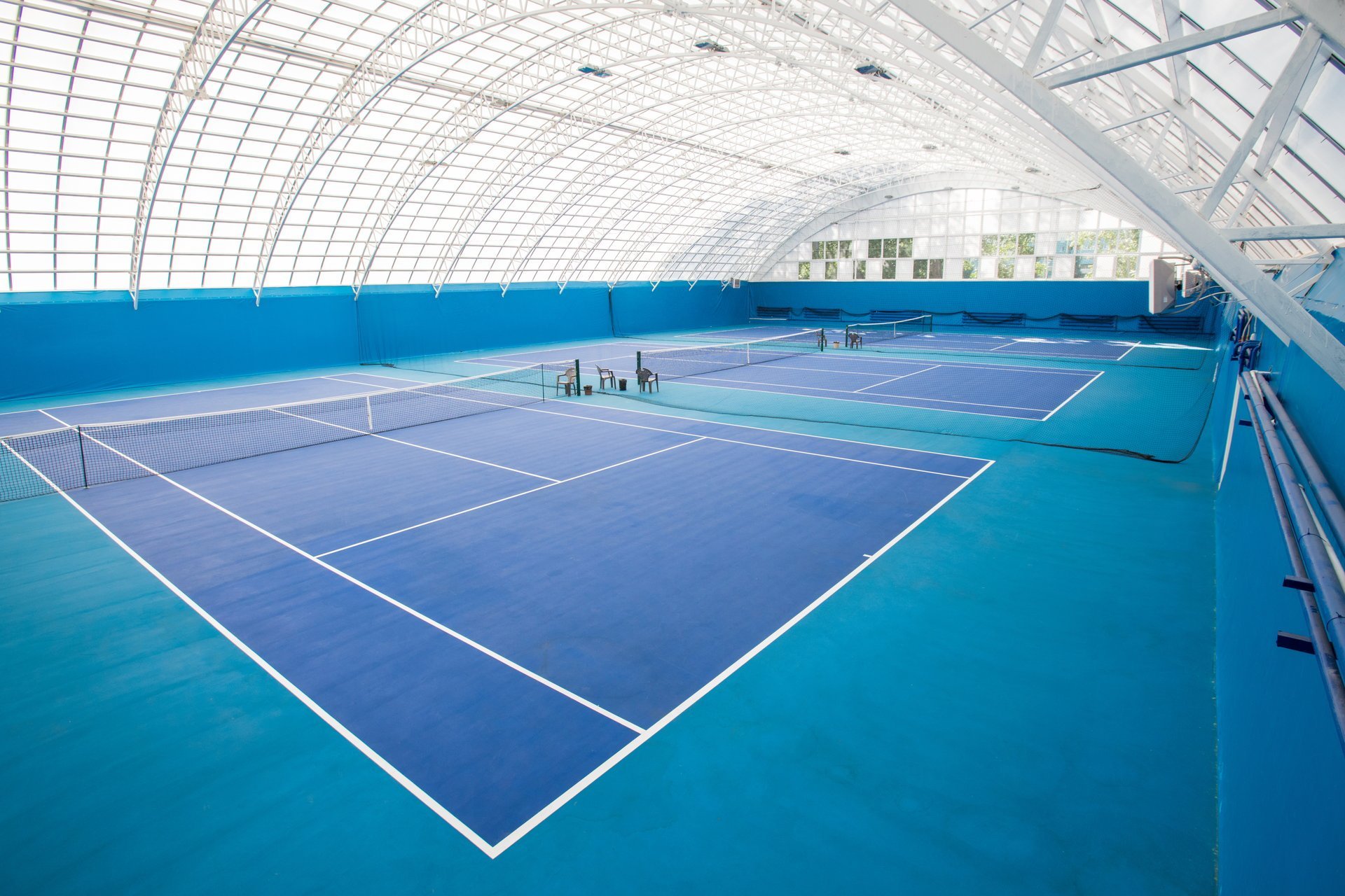 Modern indoor tennis court with vibrant blue surface
